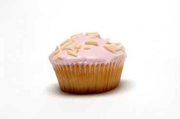 Single pink-iced cupcake covered in white chocolate curls