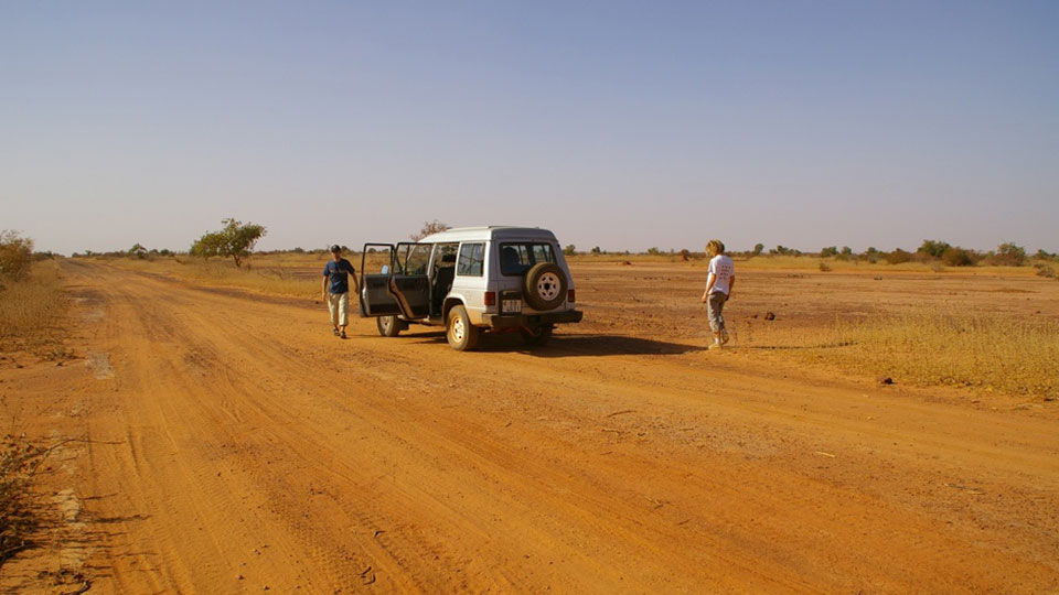 Two people stood outside a car on a dessert track