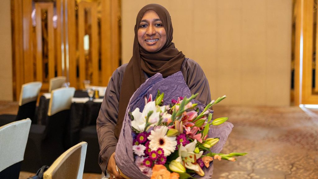 Safra Razeek smiling and holding a bunch of flowers