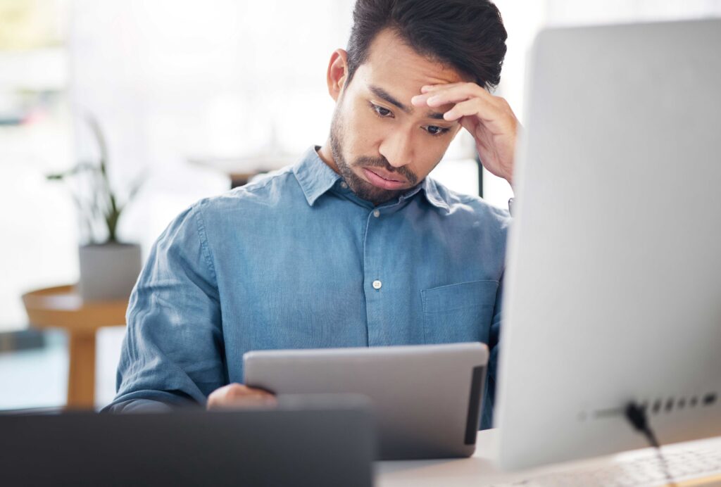 Man staring confused at a tablet and sighing