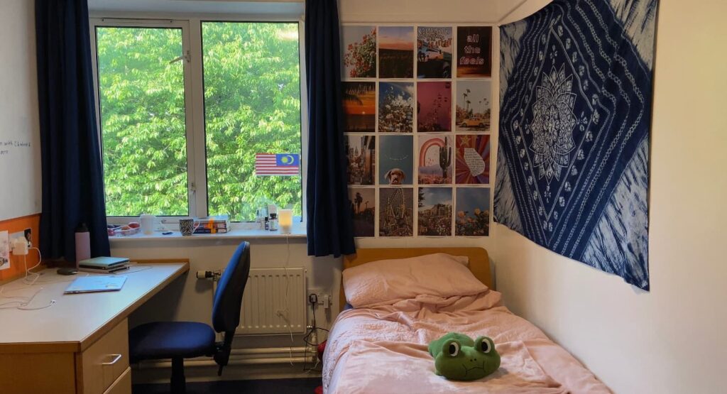 University bedroom with a bed on the right and desk and chair on the left
