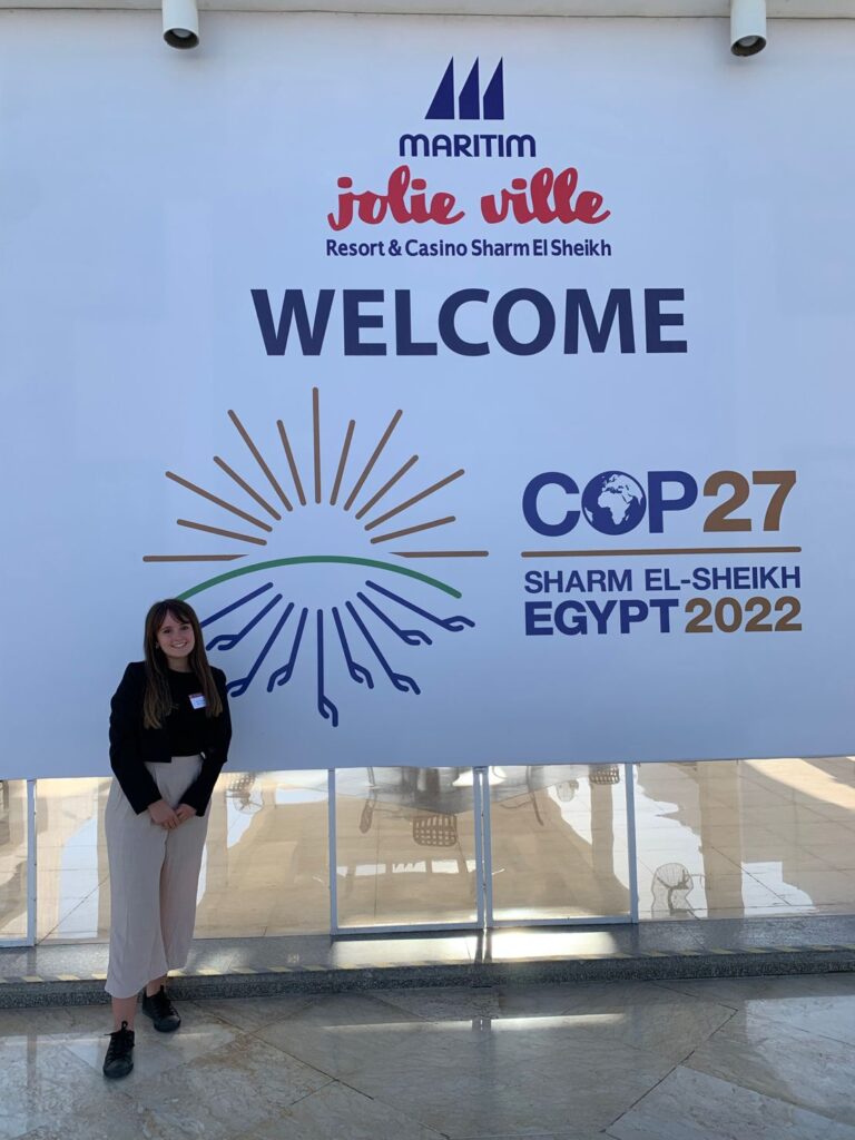 Erin in front of a COP27 banner