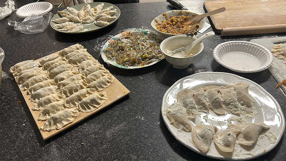 A kitchen counter with plates and trays of homemade dumplings