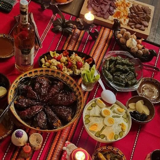 A table covered in a red tablecloth, set with traditional Bulgarian Christmas food and drink