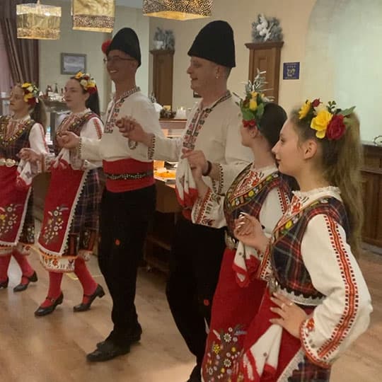 A group of six people - two men and four women - performing a traditional Bulgarian dance