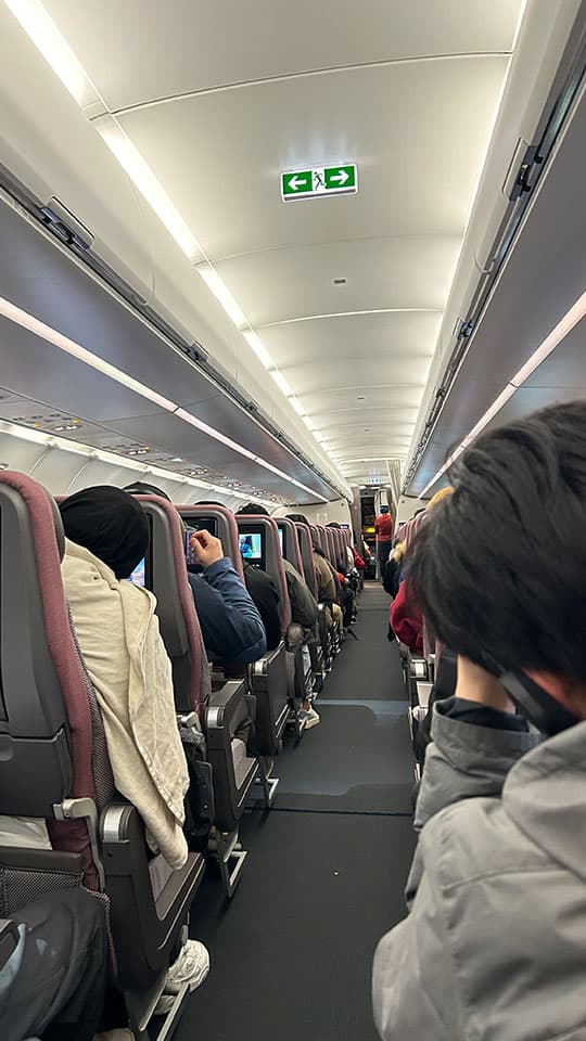 A view looking up the aisle of an aeroplane, showing passengers in their seats