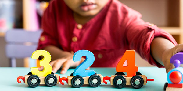 A child playing with toy numbers 3, 2 and 4 on wheels