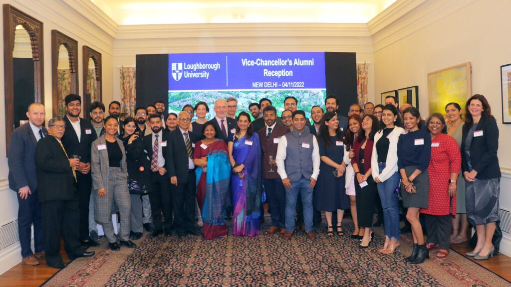 A group of people posing in front of a screen with the words 'Vice-Chancellor's Alumni Reception, New Delhi'