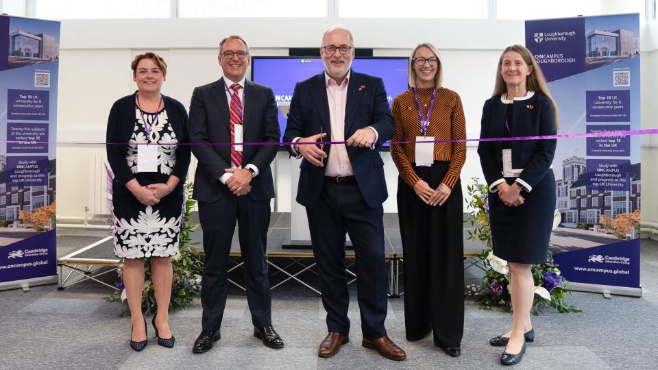 Five people standing in front of banners for the launch of 'ONCAMPUS Loughborough', Professor Nick Jennings is cutting a purple ribbon.