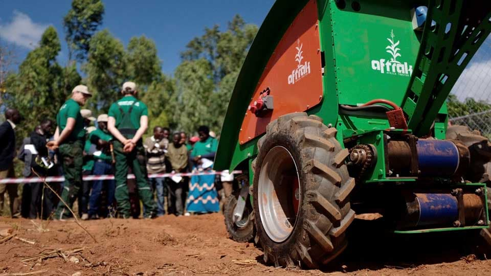 Aftrack device in use in Africa in foreground with farmers gathered in background